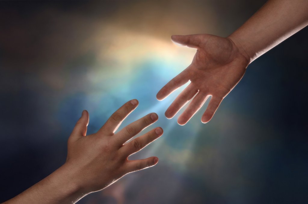 Two male hands; one reaching down to assist another hand reaching up with sunburst in the background